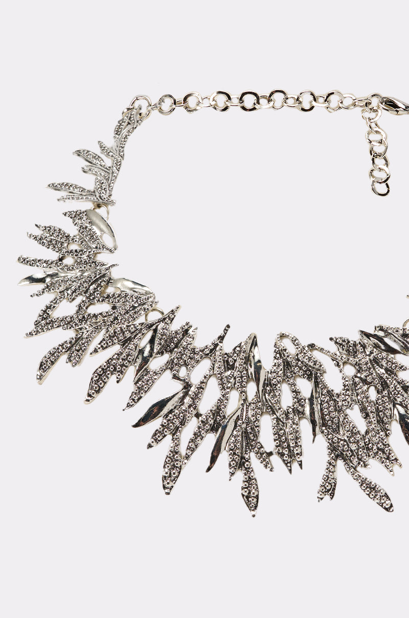 The COME THRU NECKLACE is a silver collar necklace featuring leaf-shaped metal pieces with sparkling rhinestones arranged in a fan-like pattern—a stunning, leaf-inspired accessory for any occasion. 2