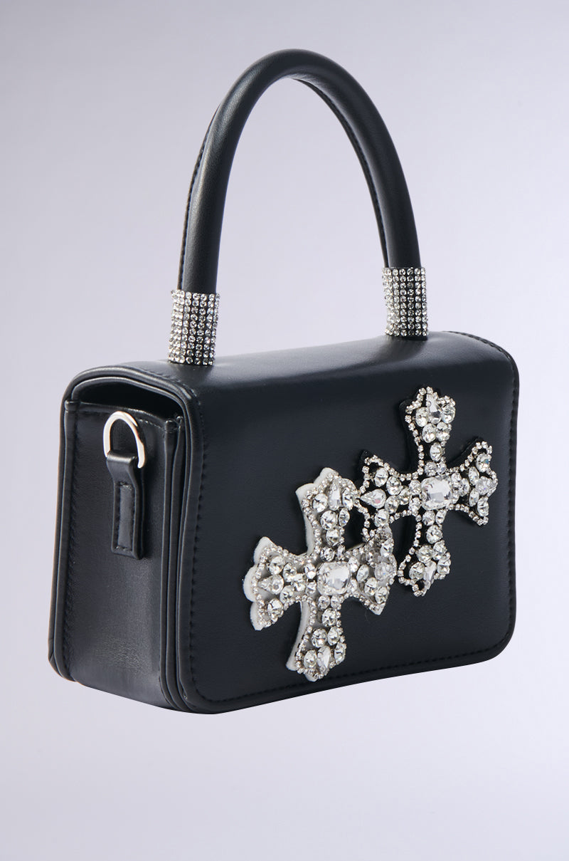 The EVERYTHING CHROME PATCH PURSE is a small black handbag with a short handle, two large jeweled crosses, and rhinestone accents. Its versatile design allows for a chic crossbody fit, perfect for day or night looks.