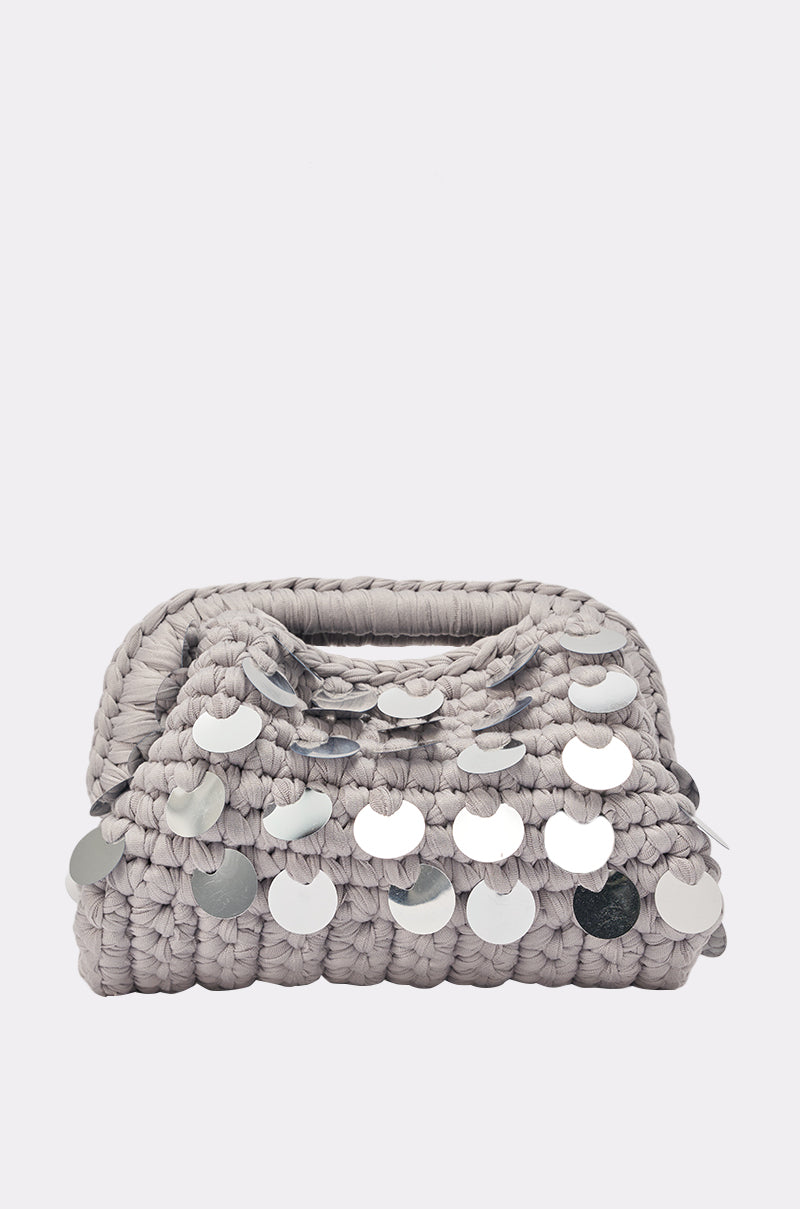 The UNDER THE LIGHTS CROCHET SEQUIN CLUTCH is a small, light gray handwoven bag with shiny silver sequins on the flap and a built-in handle, making it perfect for special occasions. 0