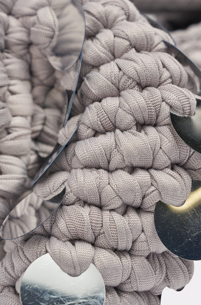 Close-up of the UNDER THE LIGHTS CROCHET SEQUIN CLUTCH, a chunky light gray bag featuring large shiny metallic sequins for a textured, reflective look—an ideal statement accessory for any party. 3