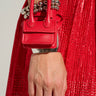 A person wearing a shiny red dress holds the RUNWAY CHIC BAG BRACELET around their wrist. They have several silver beaded bracelets that accentuate the vibrant color of this multifunctional accessory, adding a touch of elegance to their ensemble.