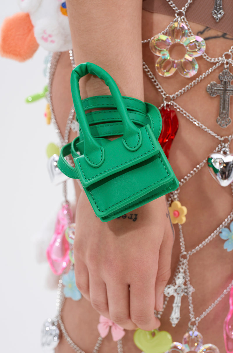 A hand wears the IN MY BAG BRACELET, featuring mesh adorned with colorful charms, flowers, and metallic crosses—showcasing a multifunctional accessory that seamlessly blends style and versatility.