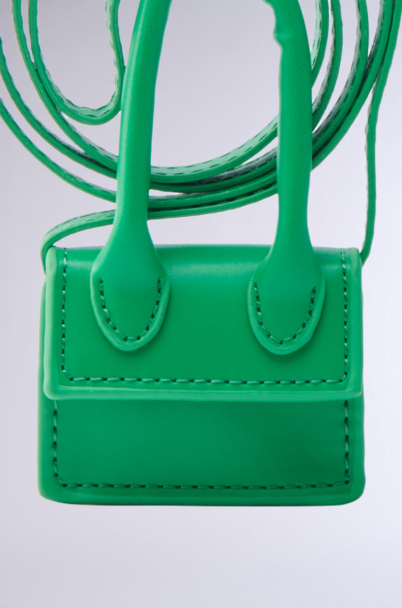 The IN MY BAG BRACELET, a small, bright green faux leather accessory with visible stitching and multifunctional design, features a long strap and two short handles, displayed against a plain light background.