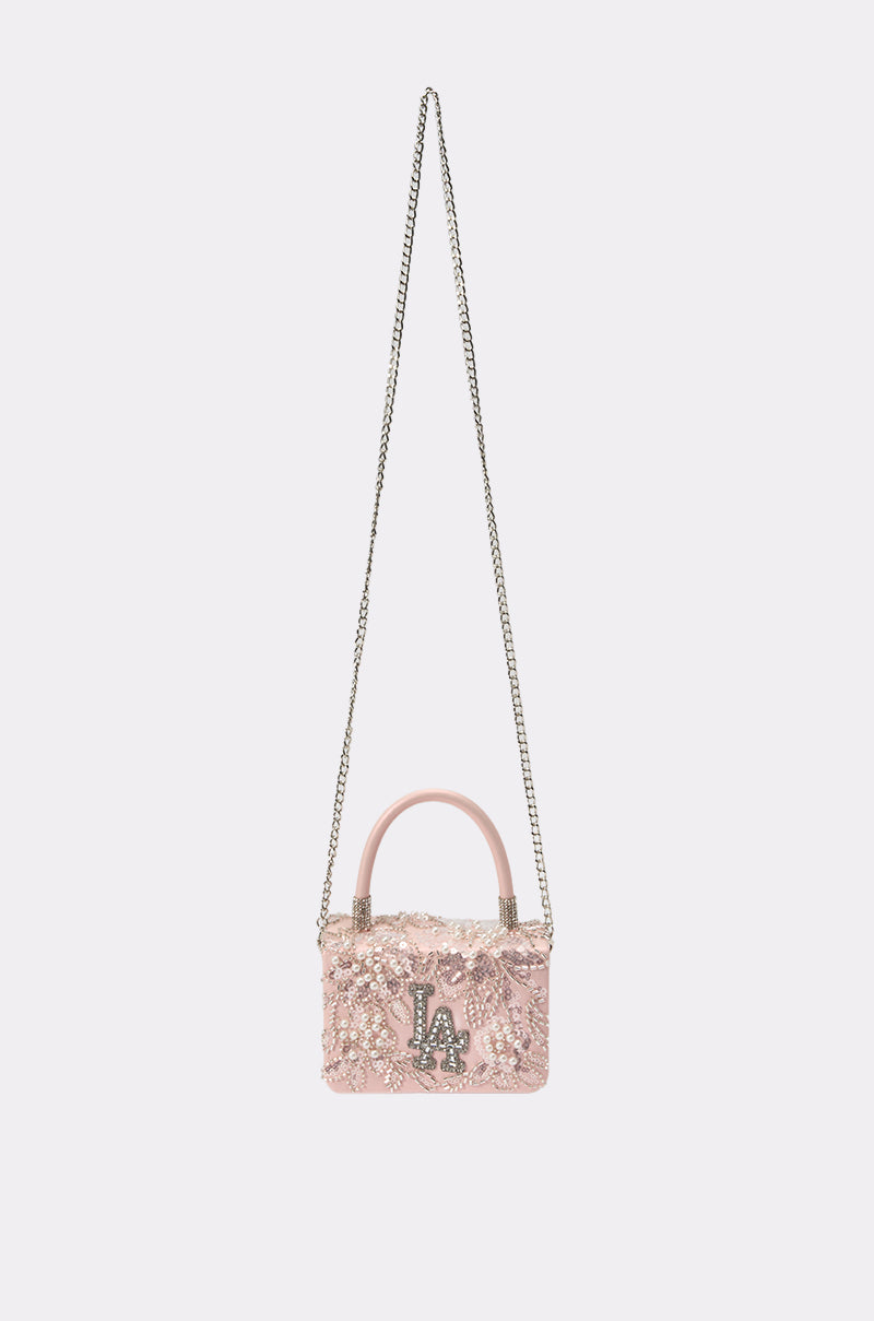 The HEARD U PURSE is a pink faux leather mini handbag with sequins, a silver "LA" emblem, short handle, and long silver chain strap, shown on a plain light background. 2