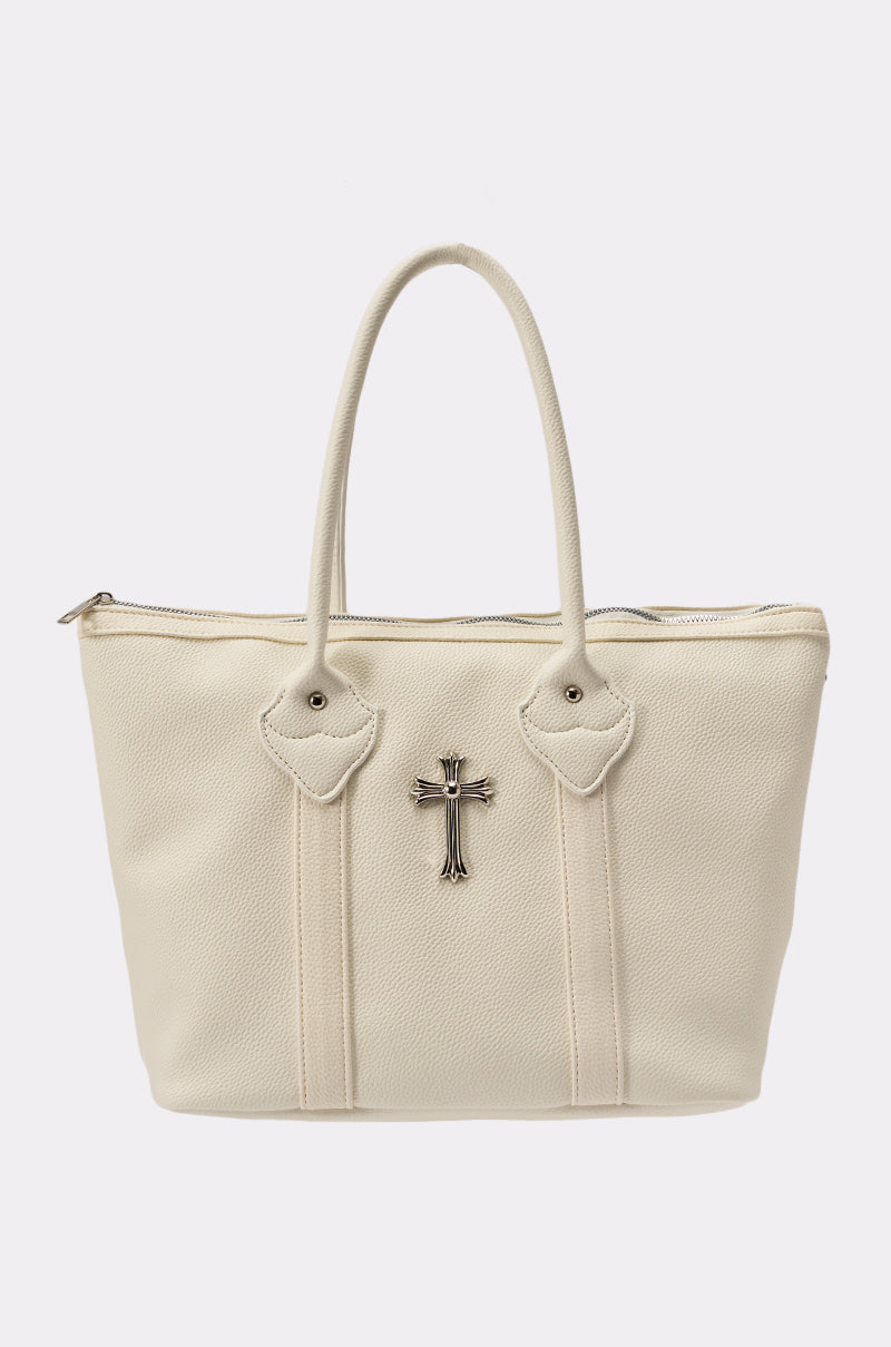 The WITH IT SNAP BAG is a cream-colored, oversized faux leather shoulder bag featuring two handles, silver-tone hardware, a zippered top, and a silver cross emblem on the front, shown against a plain white background. 0
