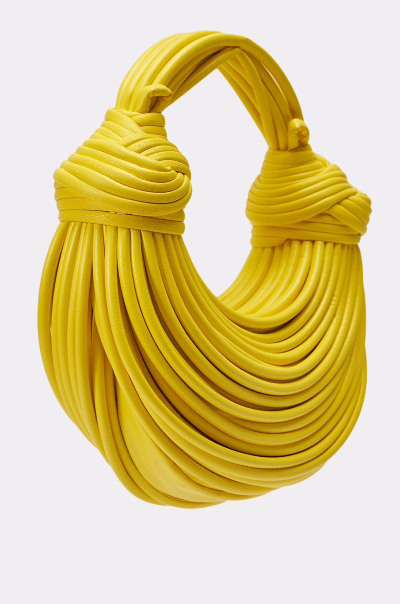 The BANANA SPLIT WHO PURSE is a bright yellow fringe handbag with thick, flexible tubular loops and artistically wrapped handles—an eye-catching, sculptural statement accessory. 2