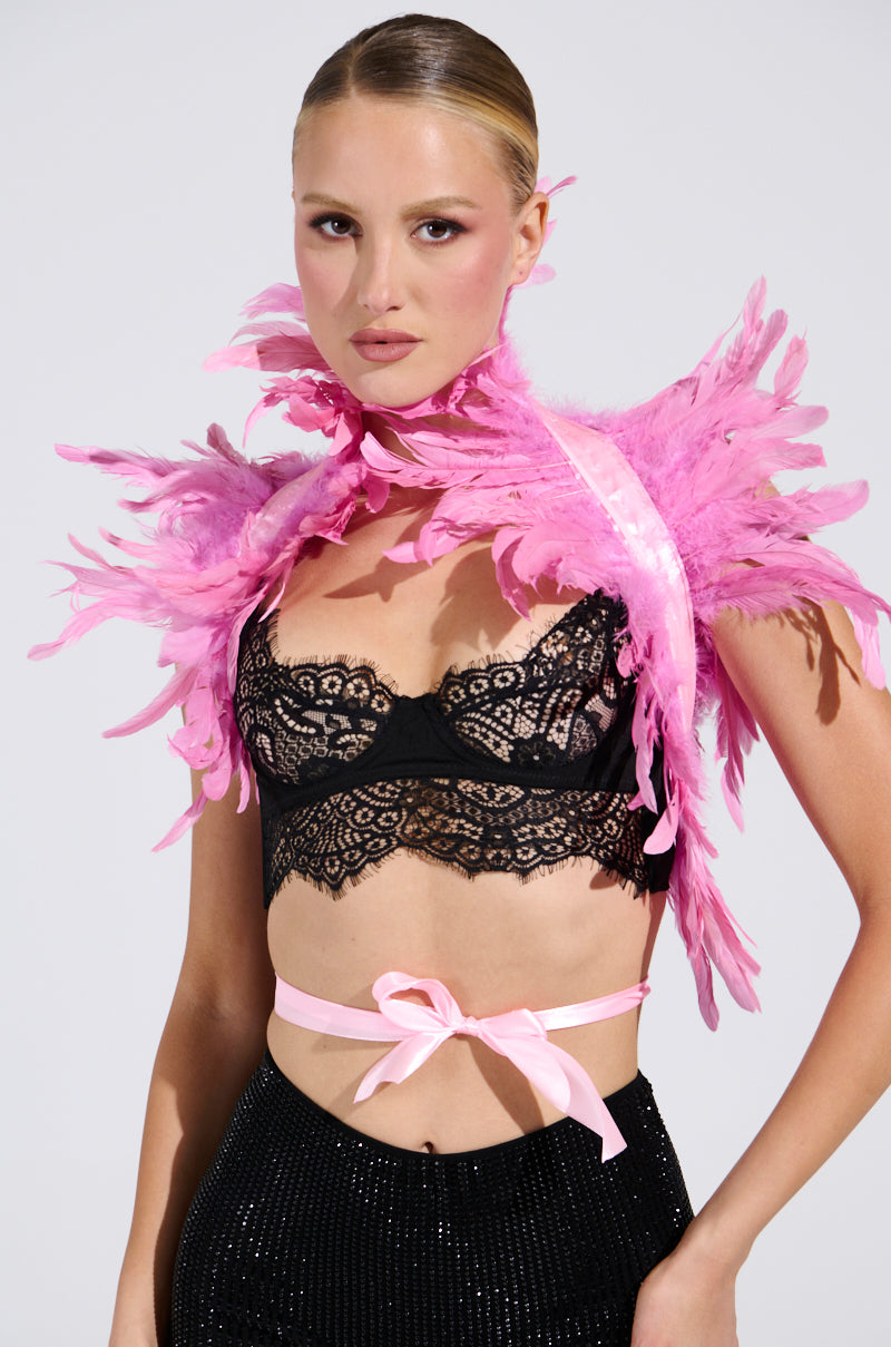 A person in a black lace top, black sequin skirt, and the HERE FOR THE DRAMA FEATHER BOLERO as a statement piece. The outfit is finished with a light pink ribbon at the waist. Hair is sleekly styled back, all set against a plain, neutral background. 1