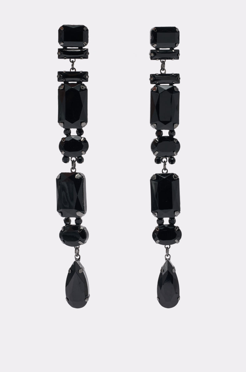 THE DRAMA BLACK STONE DANGLE EARRING features a striking arrangement of black gemstones in rectangular, oval, and teardrop shapes, elegantly set in a long, vertical design. Styled against a plain background, these bold drop earrings make the perfect statement piece for any evening ensemble.