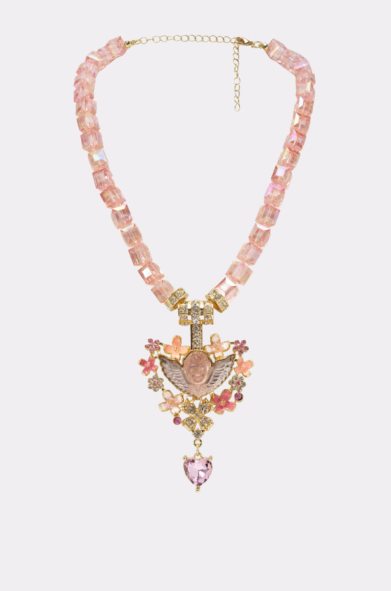 The ANGEL VIBES NECKLACE features chunky pink rectangular beads, a central gold pendant with pink stones and floral accents, plus a dangling pink heart gem—making it the perfect statement piece for festivals.