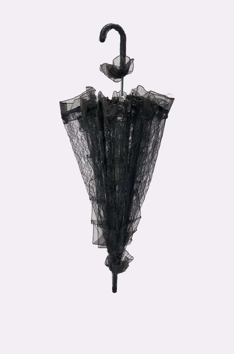 The UNDER MY SPELL LACE UMBRELLA is a vintage-style black umbrella with a curved handle, ruffled lace details, and a scalloped edge, showcased against a light gray background. 6