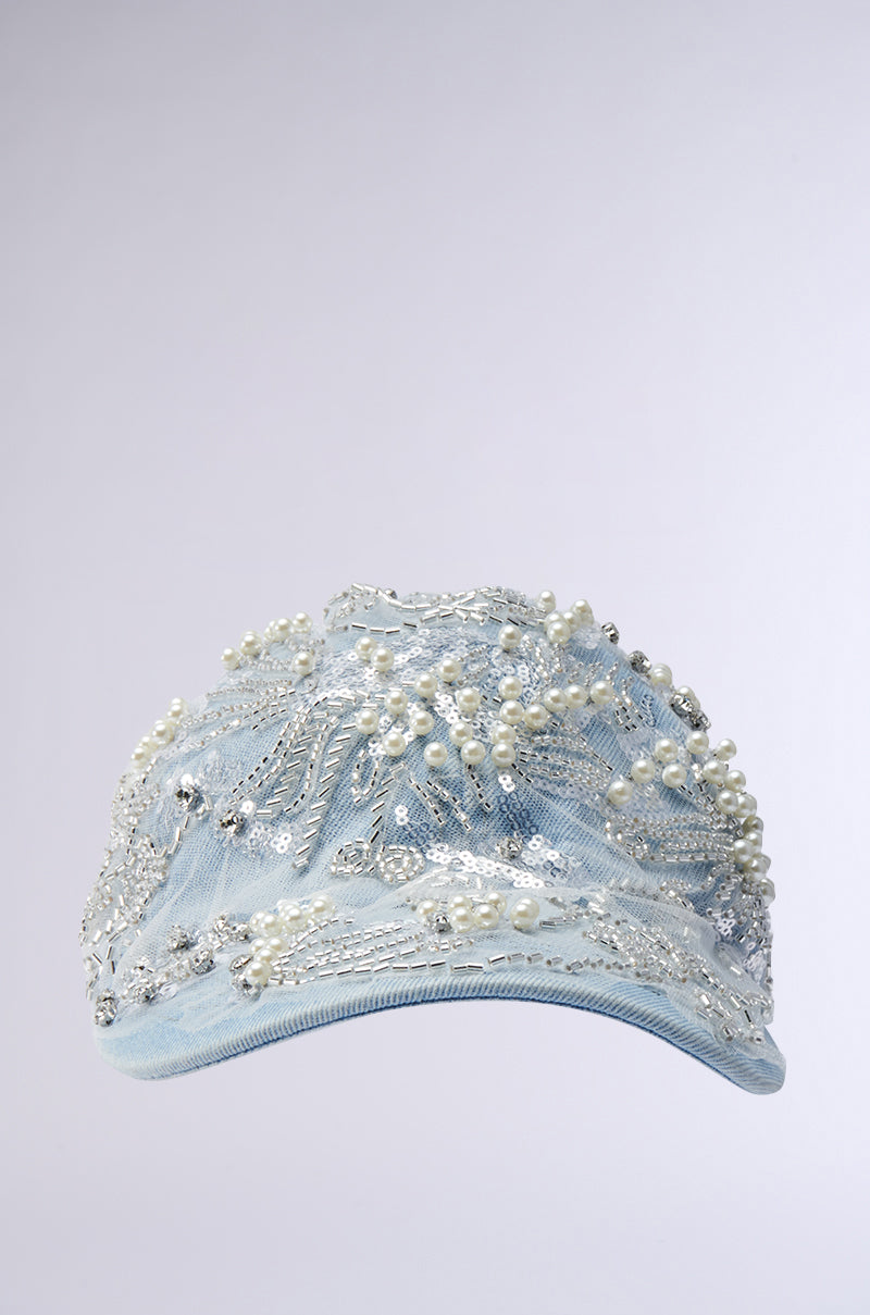 The BLESSING IN DENIM EMBELLISHED BASEBALL HAT features a light blue denim cap adorned with intricate silver embroidery and white pearls. A sequin rhinestone bead design adds decorative elegance, while the adjustable buckled strap ensures a perfect fit for this stylish casual accessory. 1