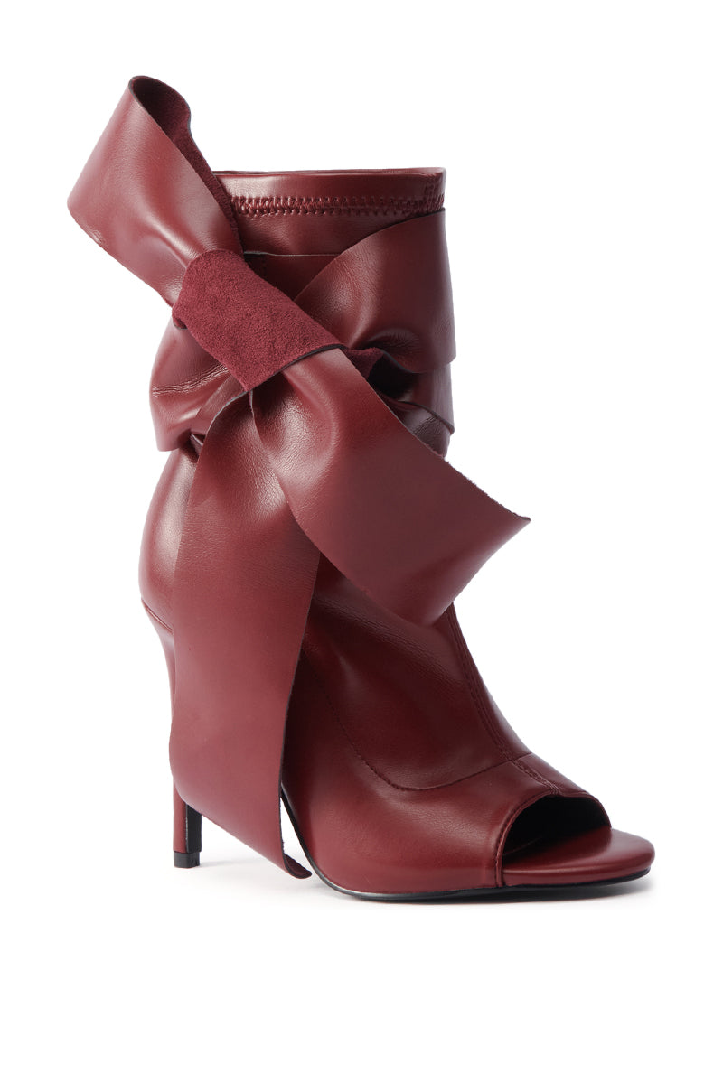 The AZALEA WANG KLARICE BURGUNDY STILETTO BOOTIE features vegan leather, a peep toe, and a large matching ribbon bow around the ankle.
