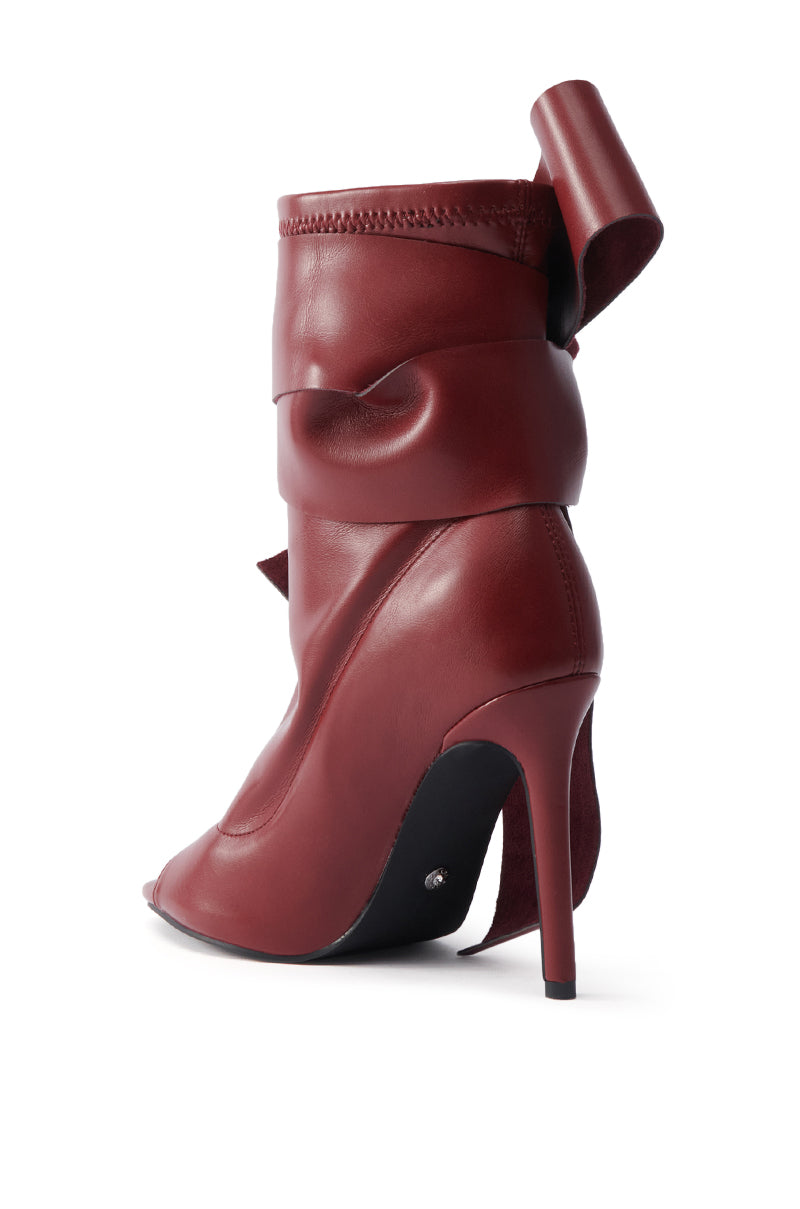 The AZALEA WANG KLARICE BURGUNDY STILETTO BOOTIE features burgundy vegan leather, a peep toe, wraparound sculpted design, decorative folded back detail, and a slender high heel for an elegant touch.