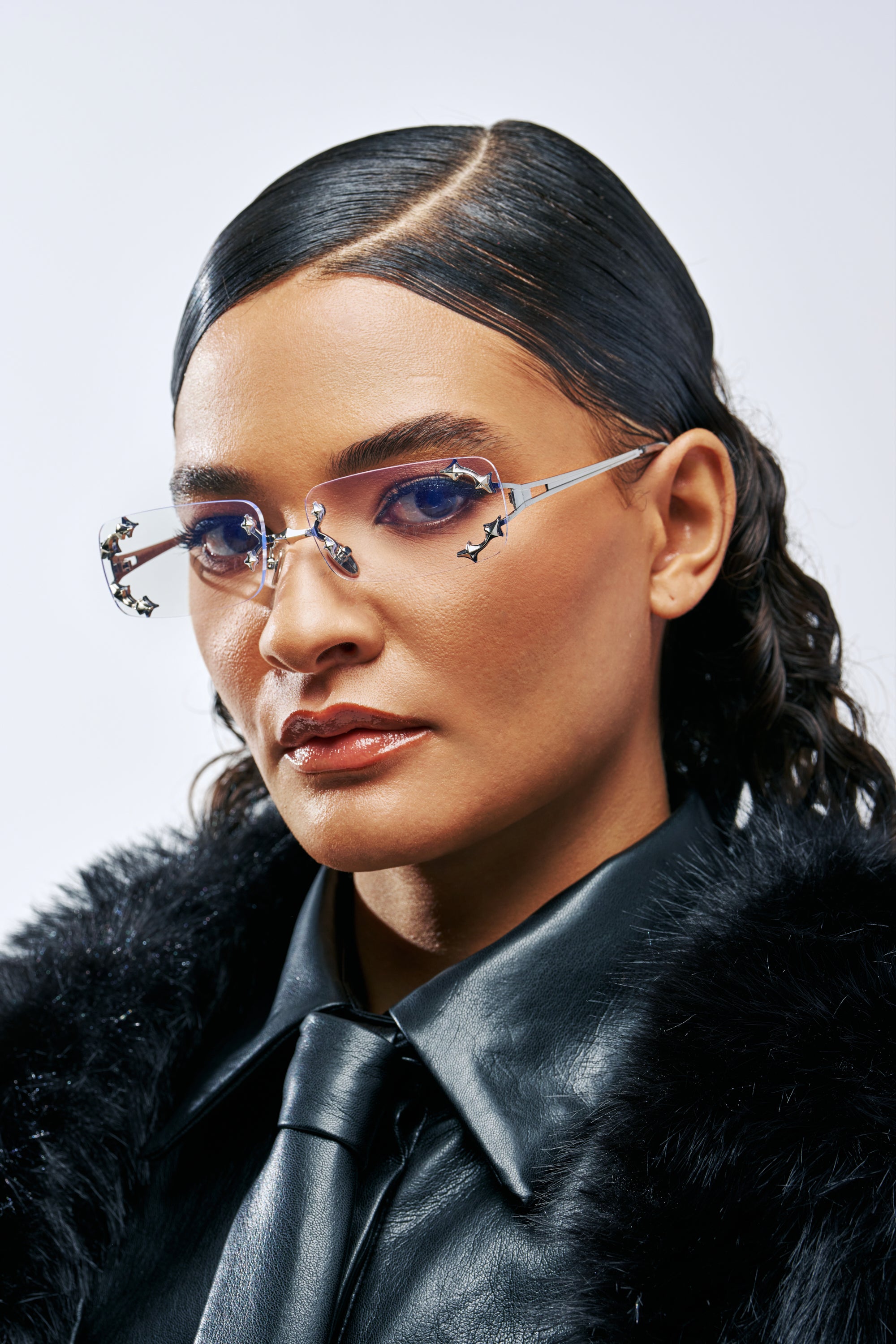 A person wears SOFT BUT UNTOUCHABLE FRAMES, which are frameless glasses featuring silver hardware and small cat-shaped accents on the lenses.