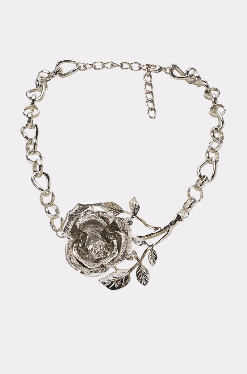 The ROSE REBEL LINK NECKLACE is a chunky silver link necklace showcasing a large, engraved rose pendant with detailed leaves and a branching stem, set against a plain white background—a perfect romantic date night accessory.