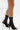 A person wears the AZALEA WANG KOHINA BLACK MESH SOCK DETAIL SANDAL—featuring sleek stiletto heels and faux leather straps—while standing against a plain white background.