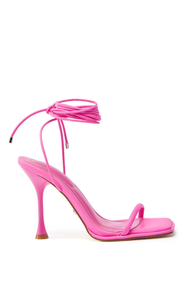 The AZALEA WANG KOHINOOR PINK BOOTIE STILETTO in vegan leather features a square toe, thin straps across the toes and ankle, and a stiletto heel. The wrap-around ankle strap finishes with metallic tips, all set against a white background.