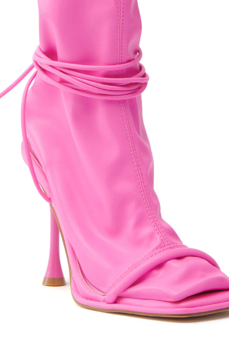 The AZALEA WANG KOHINOOR PINK BOOTIE STILETTO is a bright pink vegan leather bootie with an open square toe, thin stiletto heel, and wrap-around ankle laces. The smooth, glossy material adds to its unique design.
