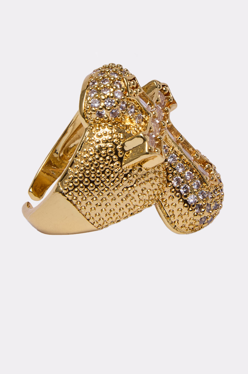 The LUXE CROSS RING is a faux gold ring featuring sparkling rhinestone details in a cross design, displayed against a plain white background. 2