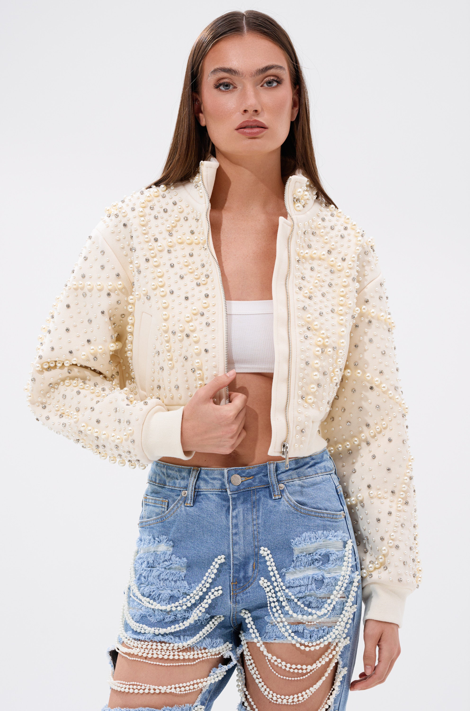 A woman wears the GOODIE TWO SHOES EMBELLISHED BOMBER—a jacket from AKIRA Label decorated with faux pearl rhinestones. 1