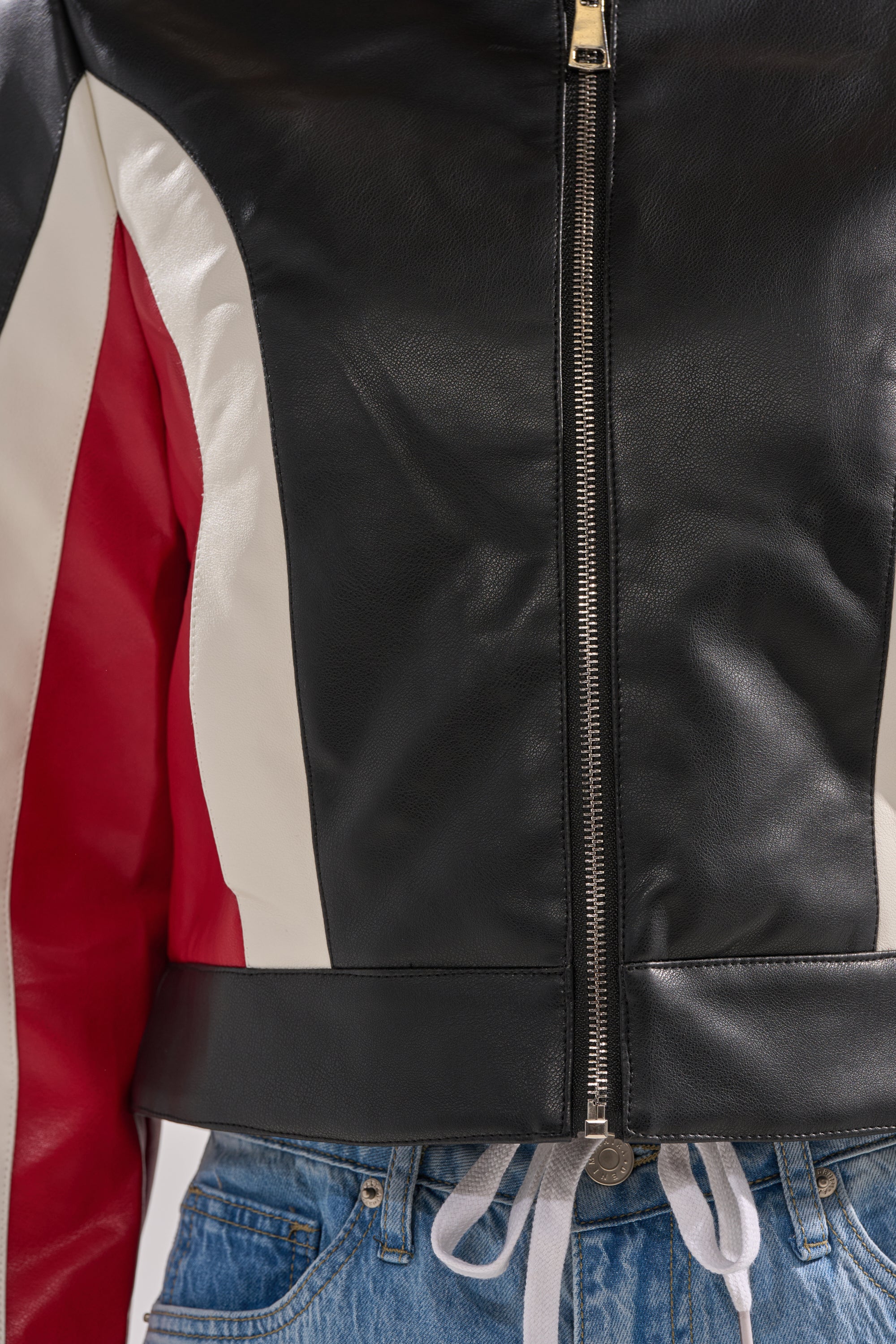 Close-up of a person wearing the ON YOUR MARKS RACER MOTO jacket in black with white and red sleeve stripes, paired with blue jeans and a visible white drawstring underneath. 9