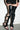 A person wearing a black sheer mini skirt and AZALEA WANG KRISTINE BLACK STRAPPY UPPER GLADIATOR SANDAL stands indoors on a light-colored floor.