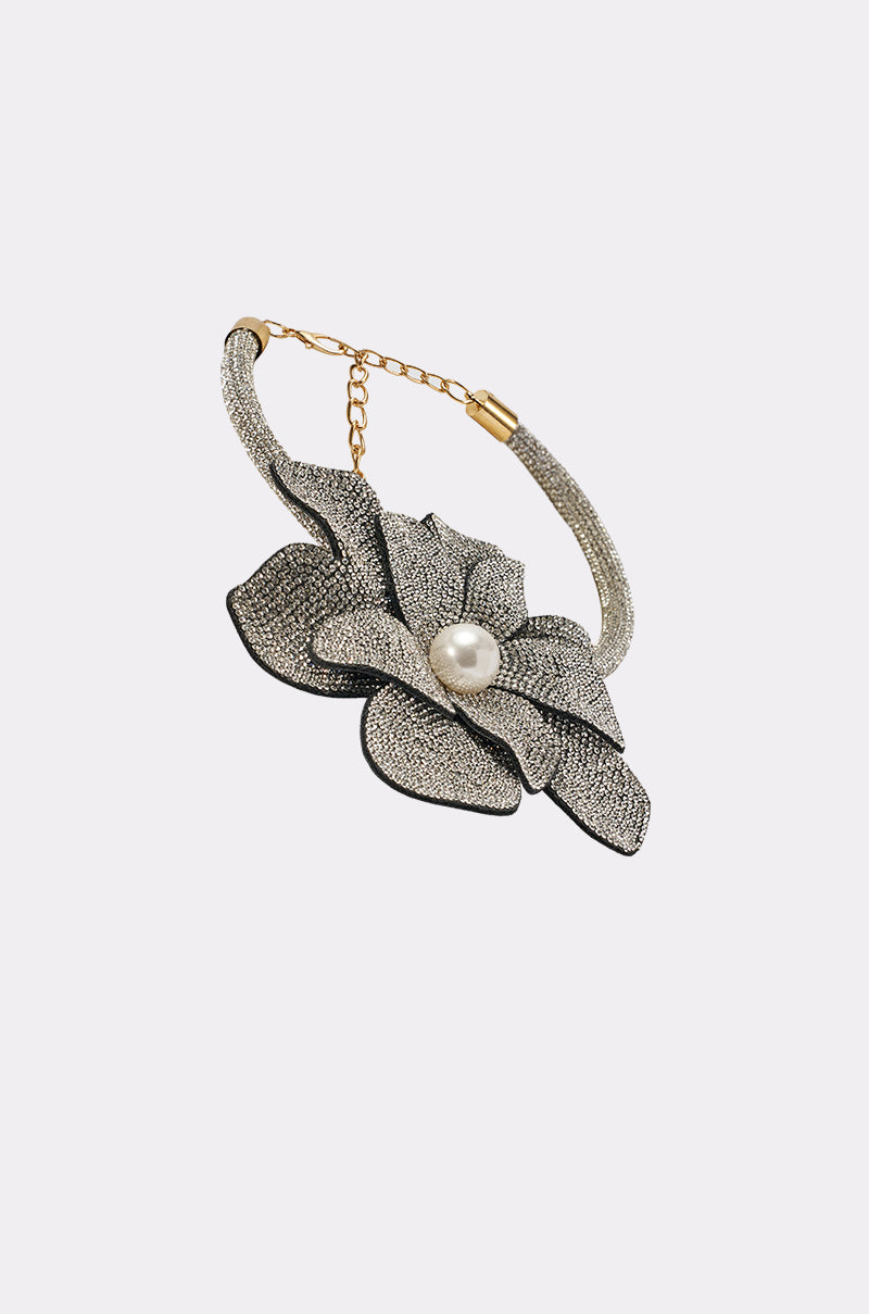 The HOLIDAY READY NECKLACE features a gold chain with a large, textured silver flower pendant accented by black edges and a white pearl-like bead at its center, beautifully displayed on a plain white background. 2