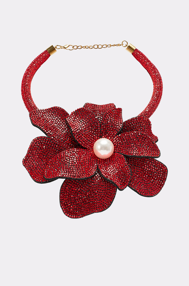 The IN BLOOM NECKLACE features a bold red flower with textured petals and a central pearl, set on a red beaded collar with a gold chain clasp—perfect for making a statement. 2