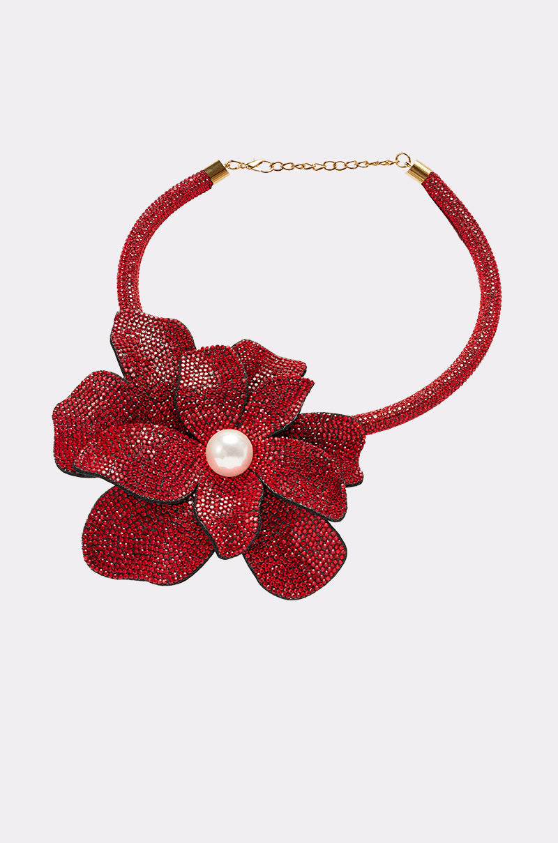 The IN BLOOM NECKLACE is a bold statement piece featuring a sparkling red floral pendant with layered petals and central pearl, set on a matching red beaded band with gold clasp and chain extender. 3