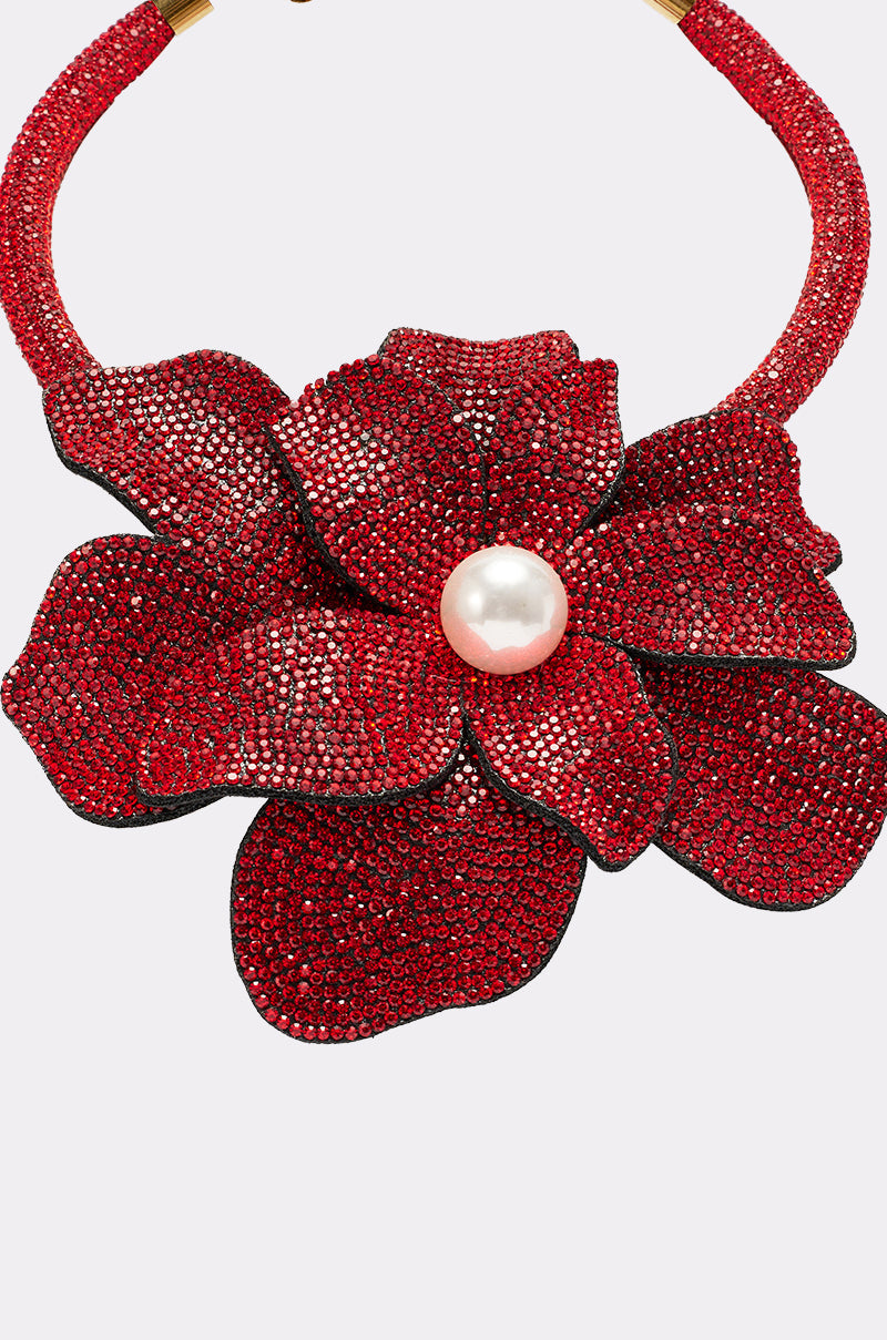 The IN BLOOM NECKLACE is a sparkling floral statement piece with large, textured red rhinestone petals, a central pearl, and a rhinestone-encrusted band for extra glamour. 4
