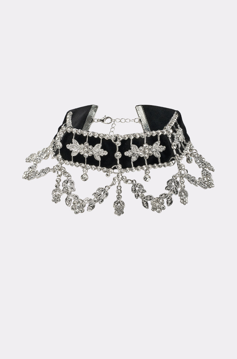 The WHERES THE PARTY CHOKER NECKLACE is a black velvet choker with silver cross accents and dangling floral crystal charms, finished with an adjustable chain clasp. 0