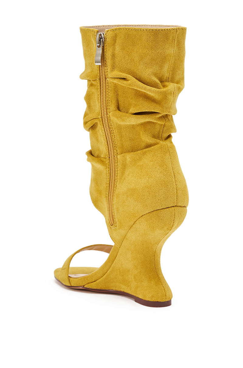 The AZALEA WANG KYVELISA MUSTARD WEDGE OPEN TOE BOOTIE features yellow faux suede, a ruched design, side zipper, open toe, and sculptural wedge heel, shown from a back-side angle on a white background. 5