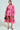 Wearing a vibrant pink plaid coat over the ELLE TWEED MINI DRESS, they hold a black handbag and wear black pointed heels, exuding Legally Blonde's confident style against a plain background.