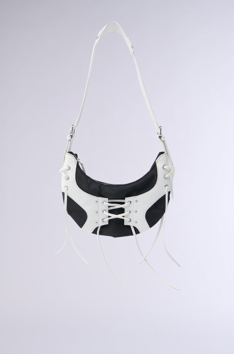 The GO SPORTS LACEUP PURSE is a black shoulder bag with white faux leather accents, a lace-up corset-style front, and a white adjustable strap, displayed against a plain light gray background.