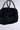 Introducing the TOO FURRY TO CARE FAUX FUR BAG, a chic accessory that features short leather handles and an elegant black faux fur design. This handbag's soft and plush texture makes it perfect for adding style and comfort to any occasion while sitting beautifully against a light gray backdrop.