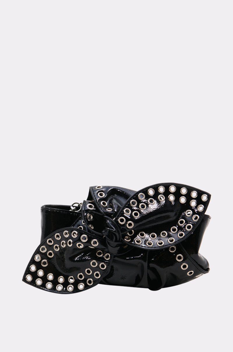 The FASHUN BABES GROMMET CLUTCH is a shiny black patent PU bag featuring an oversized bow and multiple silver grommets, displayed on a plain light gray background.