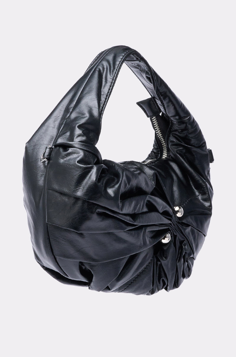 The NEW PIERCING PURSE is a black, slouchy faux leather bag with a gathered, ruched design, silver-tone hardware, single wide strap, and zipper closure, shown against a plain light background. 3
