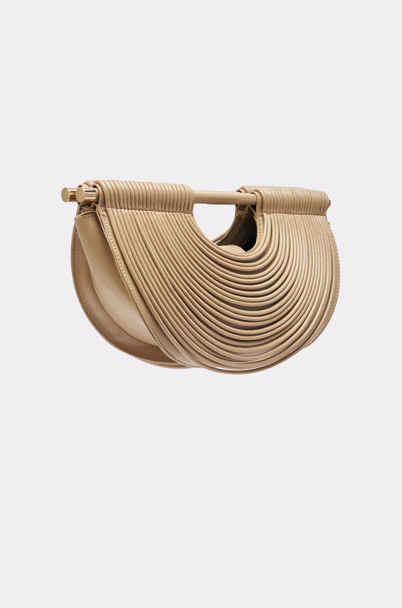 The CRESCENT CARRY-ALL PURSE is a beige faux leather bag with a ridged, layered crescent design and a small top handle, shown on a light grey background.