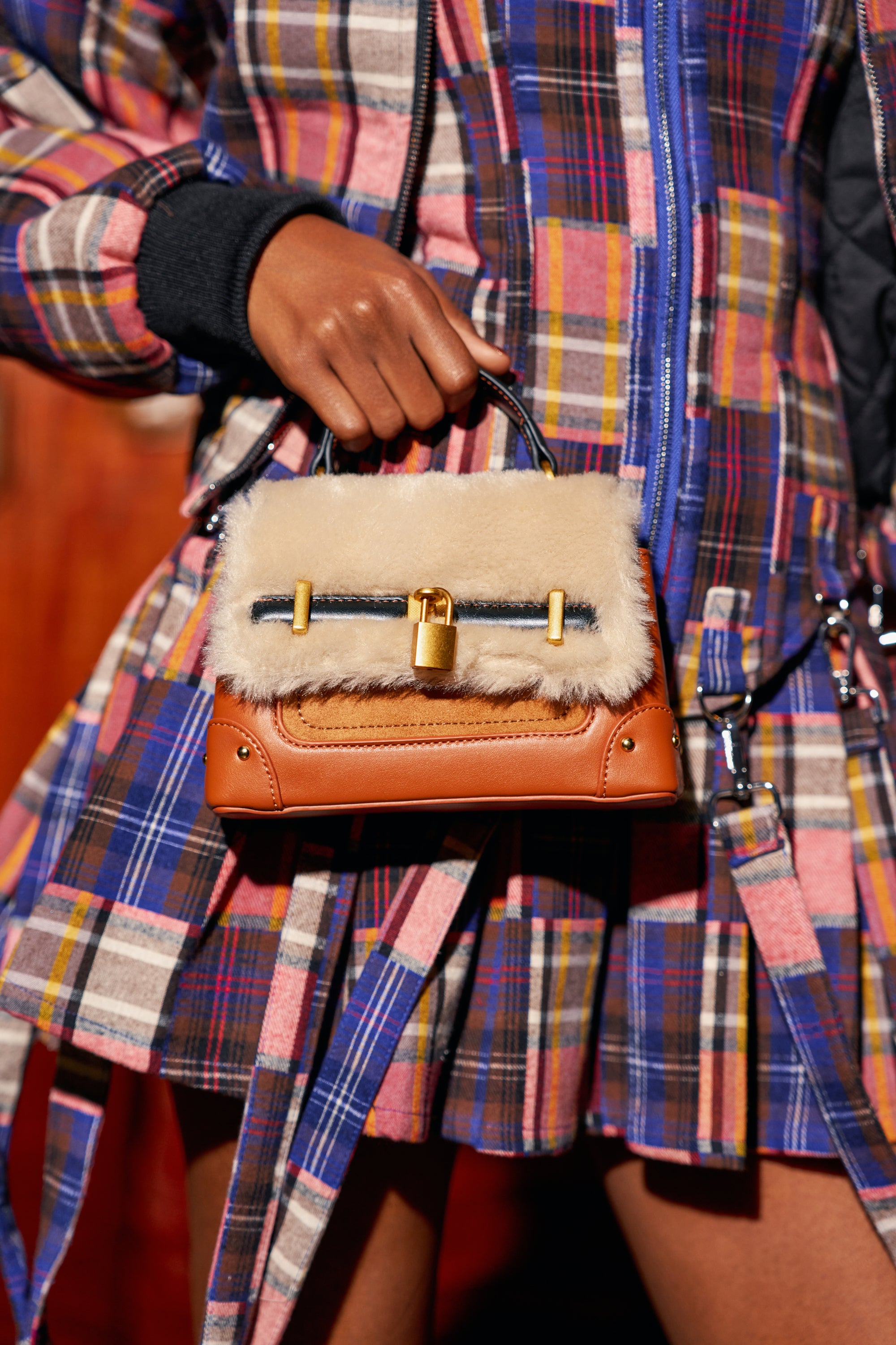 A person holding a MISS POPULAR FUR BAG, a structured beige faux fur purse featuring a cream-colored flap and a gold padlock closure.