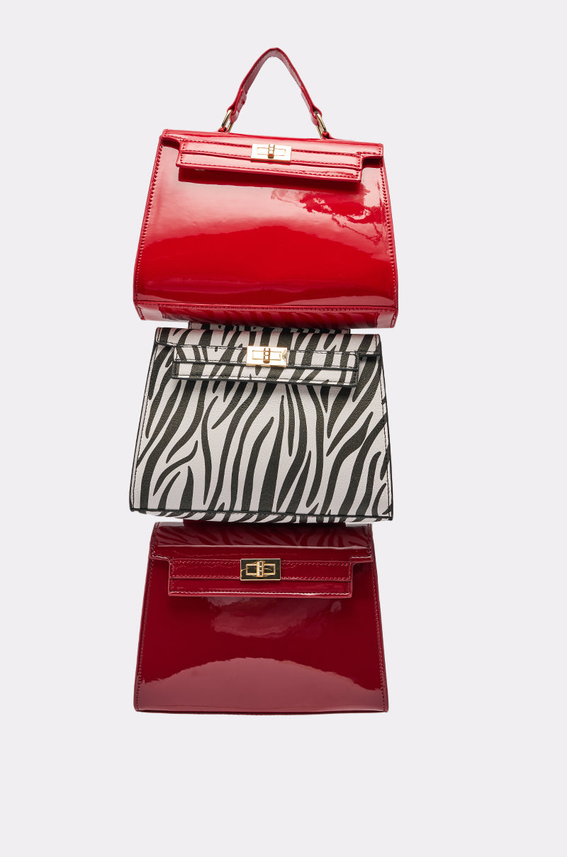 The WILD ONE STACKED DETACHABLE PURSE TRIO features three chic purses: glossy red with gold clasps on top and bottom, plus a bold black and white zebra print bag in the center, all stacked for a standout look. 0