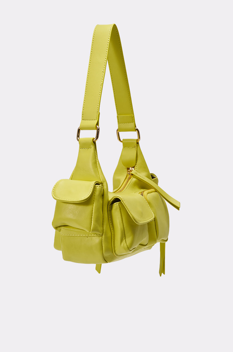 The LIFE GIVES YOU LEMONS PURSE is a neon yellow faux leather shoulder bag with gold hardware, a wide strap, and multiple utility pockets on the front and sides, shown against a plain light background. 3