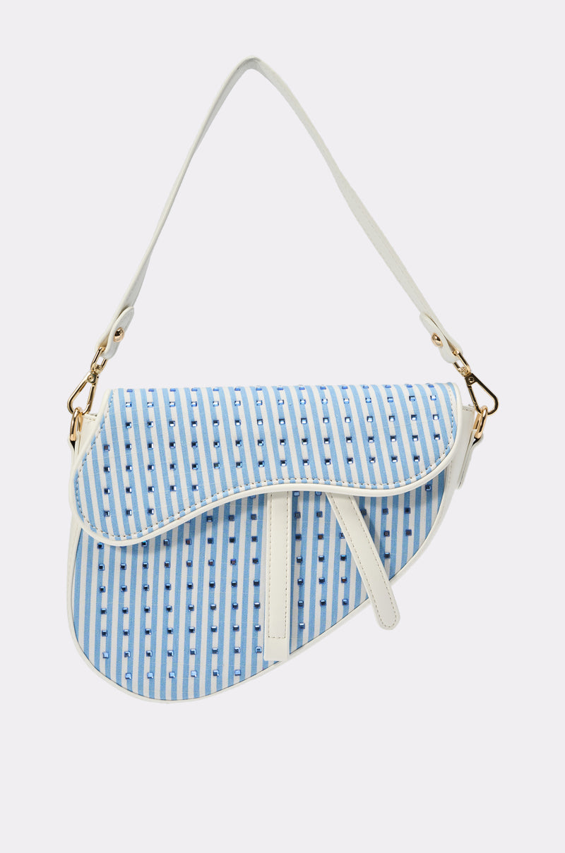 The GONE SAILING STRIPE BAG is a chic crossbody with a striking white and light blue stripe pattern, gold clasp, unique asymmetrical flap, and adjustable white strap for added style. 0