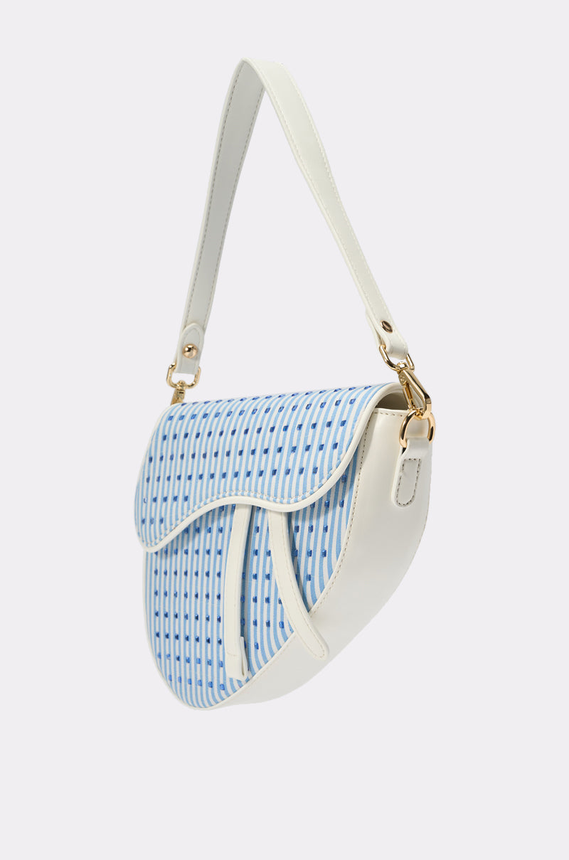 The GONE SAILING STRIPE BAG is a stylish crossbody with a curved flap, featuring blue and white stripes on the front and a white strap and trim, shown against a plain light background. 2