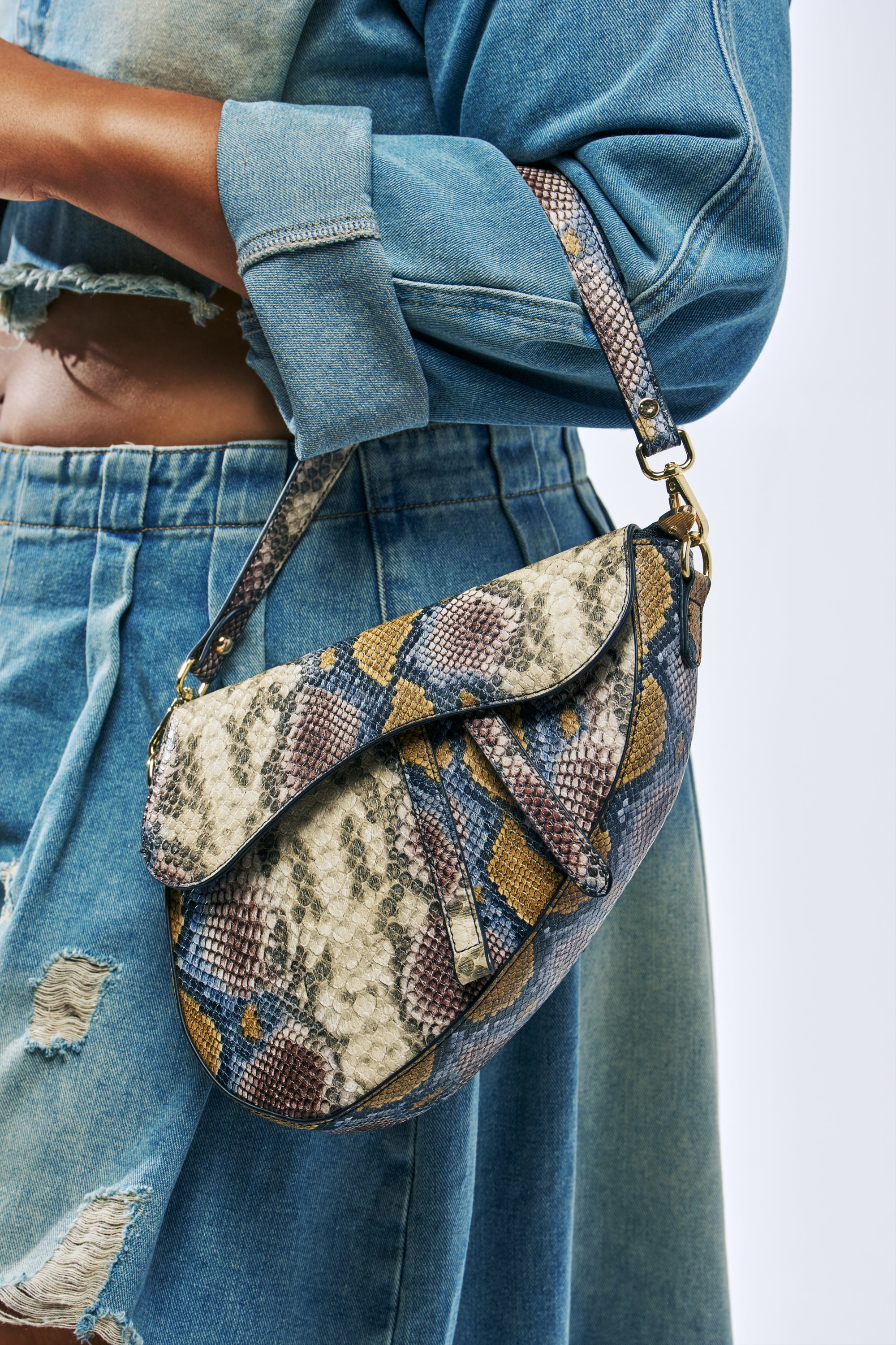 DO U GET IT PURSE, a saddle-shaped shoulder bag featuring an embossed snakeskin pattern in multicolored faux leather.