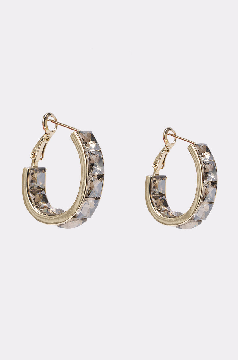 The GLITZ AND GLAM GOLD EARRING features rhinestone gold hoops with clear faceted gemstones on the outer edge, ideal as statement birthday jewelry, shown against a plain white background. 0