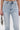 Wearing the LACE IT UP SKINNY DENIM PANT, a person holds a small silver beaded clutch in their left hand. They're styled with a corset-style top against a plain white background.