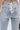 Close-up of the back of the LACE IT UP SKINNY DENIM PANT in light blue, showcasing white lace-up corset-style detailing between two back pockets with silver grommets and a bow-tied white drawstring.