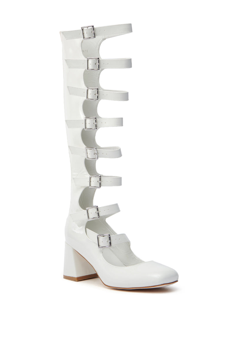 The AZALEA WANG LAIMA WHITE PATENT CHUNKY BUCKLE BOOT is a knee-high white patent leather boot with six horizontal buckle straps, featuring a chunky heel, rounded toe, and plain white background. 4