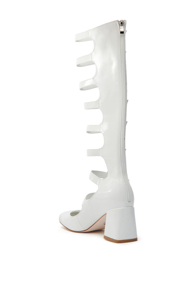 A side view of the AZALEA WANG LAIMA White Patent Chunky Buckle Boot showcases a knee-high shaft with multiple horizontal straps, a full-length back zipper, and a chunky heel, all on a plain white background. 5