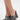 A close-up of a person wearing the AKIRA LAMONT SNAKE SANDAL CHUNKY PLATFORM, featuring gray faux leather with a snakeskin pattern and open toes, standing on a white surface.